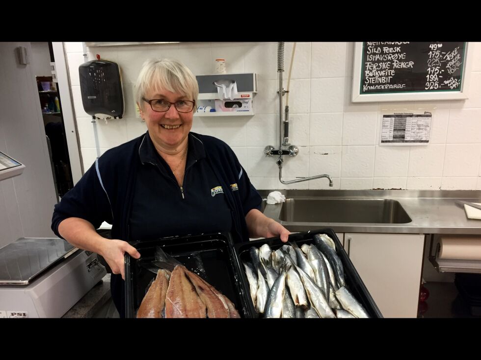 Ingjerd Høyli viser her frem to tildels glemte kulinariske matskatter, fersk småsild og gammelsei, bak disken i butikken hun jobber på Kirkenes.
 Foto: Hallgeir Henriksen