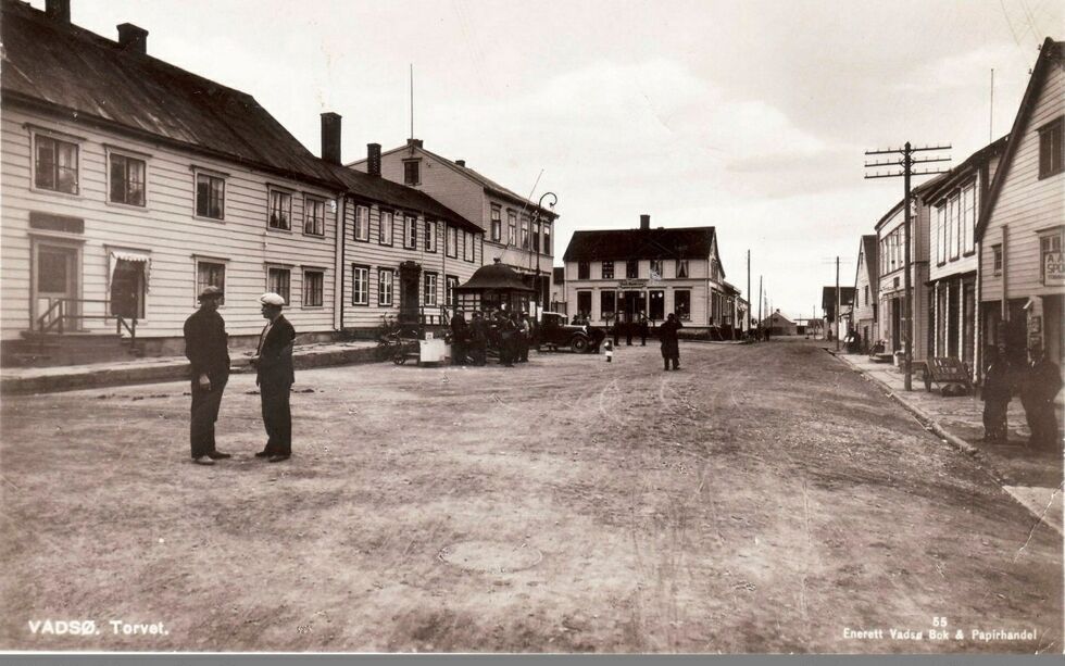 Dette bildet som viser Tollbugata i Vadsø sett fra nord mot sør, er blant de som finnes i den digitale byvandringen. Bildet, som man mener er tatt på 1930-tallet, viser torget med en del folk, lastebil og kioskpaviljong.
Foto: Vadsø bok- og papirhandel/Vadsø museum-Ruija kvenmuseum