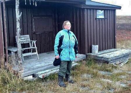 Magnhild Reisænen ved hytta si i nasjonalparken i 2016. Hun føler seg svært urettferdig behandlet av vernemakta som nekter henne å kjøre samtidig som de tillater at reindrifta og TV-kjendiser får kjøre fritt og lage spor over alt.
 Foto: privat