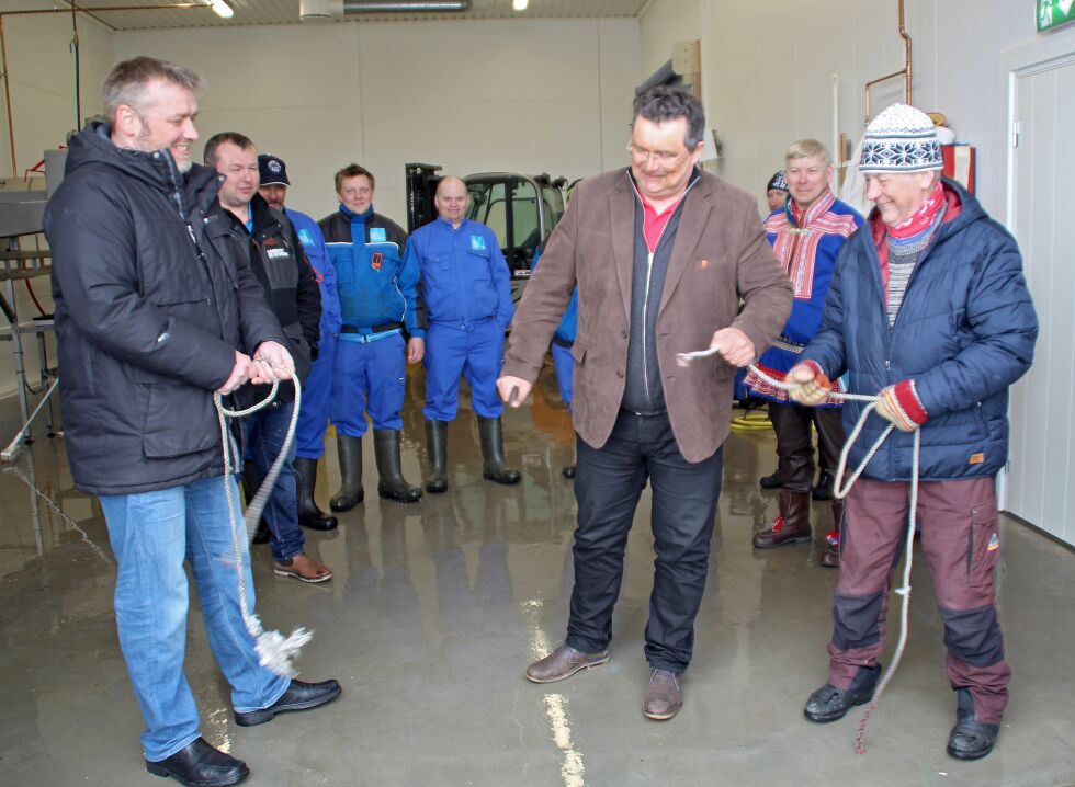 Med Ørjan Nergaard fra Lerøy Norway Seafoods (til venstre) og «fiskerhøvding» Nils Einar Mathisen (til høyre) som stødige tauholdere kunne ordfører Knut Store foreta den offisielle åpningen av det nye fiskemottaket i Nesseby – under påsyn av blant andre ansatte ved mottaket.
 Foto: Torbjørn Ittelin