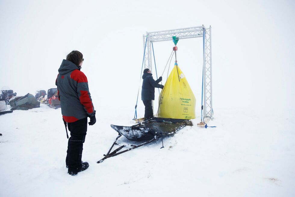 Vi startet opp til fjells med nærmest null sikt. Da vi fikk øye på den gigantiske fôrsekken som hadde blitt fraktet opp til vidda, visste vi at flokken og gjeterne var i nærheten. Dette var før vi kom til Stiipanávži. Her heises sekken opp slik at den kan flyttes. Foto: June Helén Bjørnback