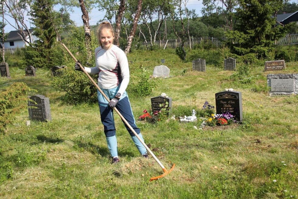 Anna Kajsa Jernsletten raker på kirkegården etter at kirkegårdsleder Bernhard Iversen har klipt gresset. Nesseby kirkegård er en naturkirkegård med lyng- og gressmark og løvtrær.
 Foto: Mari-Ann Nilssen