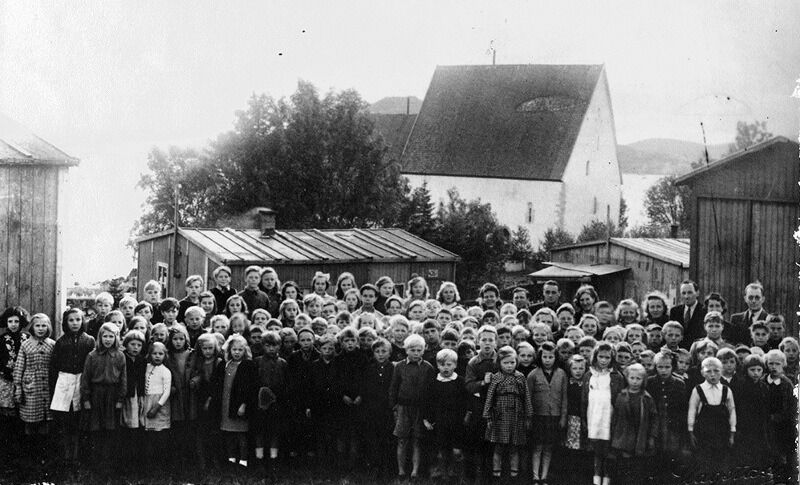 Skolebarn fra Finnmark i Trondenesleiren. I bakgrunnen Trondeneskirka.
 Foto: Bernhard Slagstad / Sør-Troms Museum