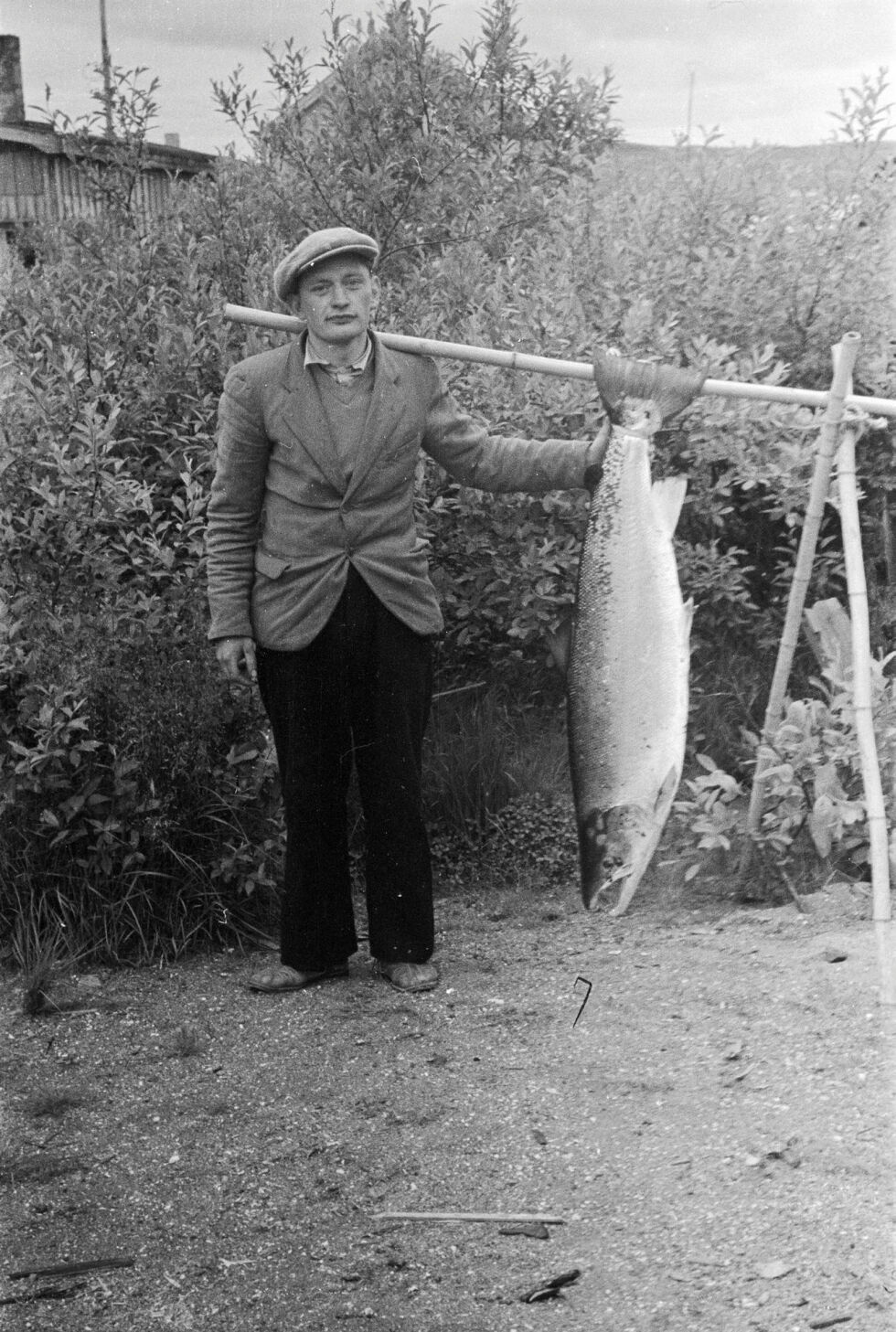 Originalen fra Kirkenes, Helge Strømme, med en av mange storlakser som han fanga nedenfor Skoltefossen i Pasvikelva i Sør-Varanger. Bildet er henta fra Arne Karlsens samling som nå er lagt ut på Digitalt museum/Finnmark fylkesbibliotek.