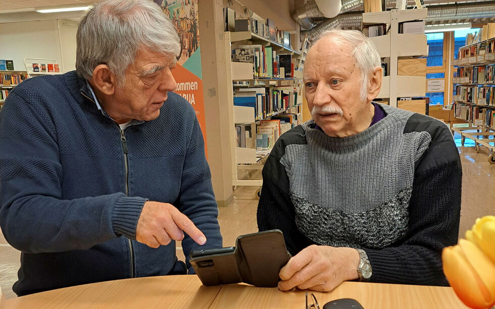 Olavi Hoikka har litt problemer med å finne kontaktene sine i telefonen. 
– Har du oppdatert? spør Cuppen. Kona til Olavi, Maja Hoikka, følger ivrig med.
 Foto: Liss Beth Gjertsen Nyby