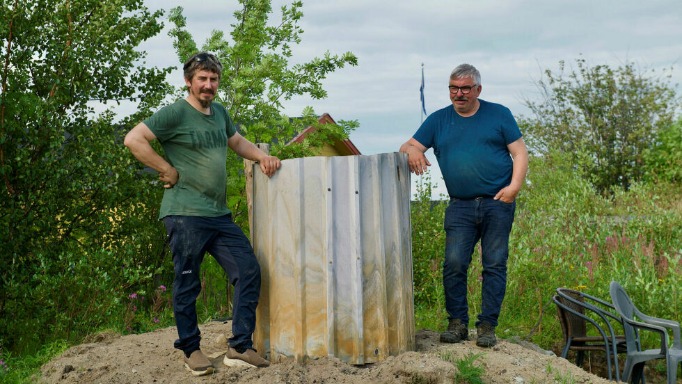 Robert Severin Pedersen og Kurt Roger Pedersen tar vare på kvænsk tradisjon og brenner tjære. Det er ikke så lett å se, men det er altså kvænflagget som ikke vaier i vinden i bakgrunnen.
 Foto: Irmelin Klemetzen