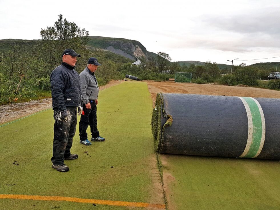 Kunstgressmattene, seks i tallet, veide hver 7-8 tonn, så det måtte solid maskinkraft til for å få dem på plass på banen, der Tor Ivar Linløkken (nærmest) og Ulf Sørflaten er blant dem som gjør frivillig innsats for at Kunes får kunstgressbane.
 Foto: Alf E. Masternes