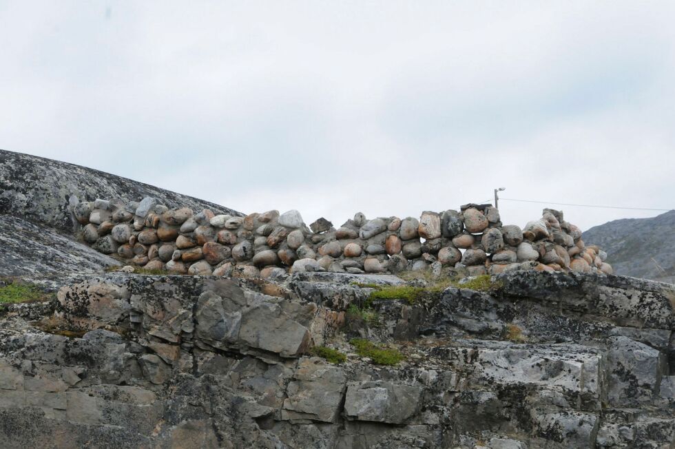 Den­ne so­li­de stein­mu­ren av run­de stei­ner ble i si tid bygd som bål­plass med vern mot nordausten. Den lig­ger på land­sida av vei­en ned til fis­ke­væ­ret Bug­øy­nes med ny­de­lig ut­sikt over byg­da og hele Var­ang­erfjor­den.
 Foto: Hallgeir Henriksen