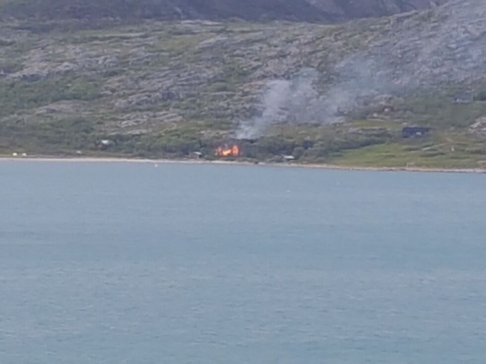 Flammene står opp fra en hytte i brann i Gandvik i Nesseby, nær kommunegrensa til Sør-Varanger.
 Foto: Privat